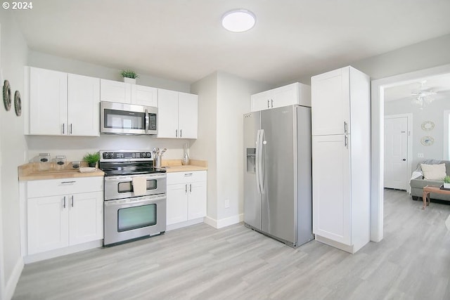 kitchen featuring stainless steel appliances, light wood-type flooring, white cabinetry, and baseboards