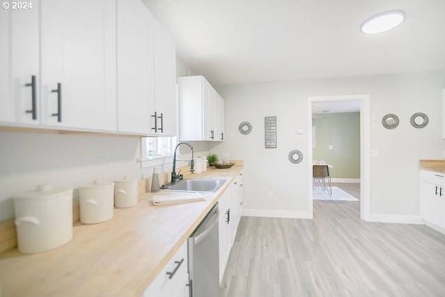 kitchen featuring light wood finished floors, light countertops, white cabinetry, a sink, and dishwasher