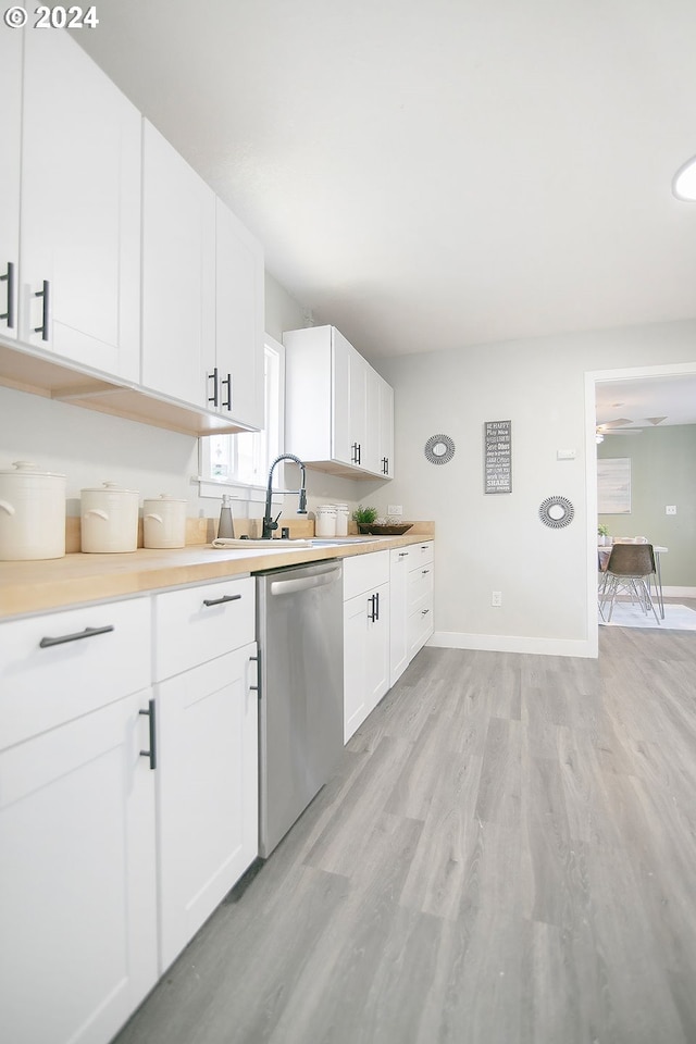 kitchen featuring light wood finished floors, baseboards, white cabinets, dishwasher, and light countertops