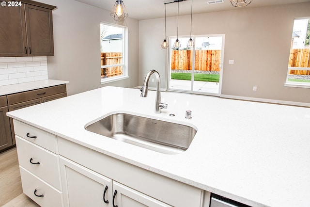 kitchen featuring dark brown cabinets, light hardwood / wood-style flooring, a healthy amount of sunlight, and sink