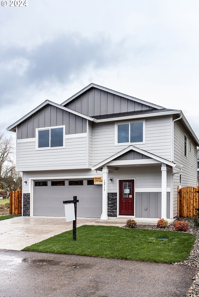 view of front of home with concrete driveway, stone siding, an attached garage, fence, and board and batten siding