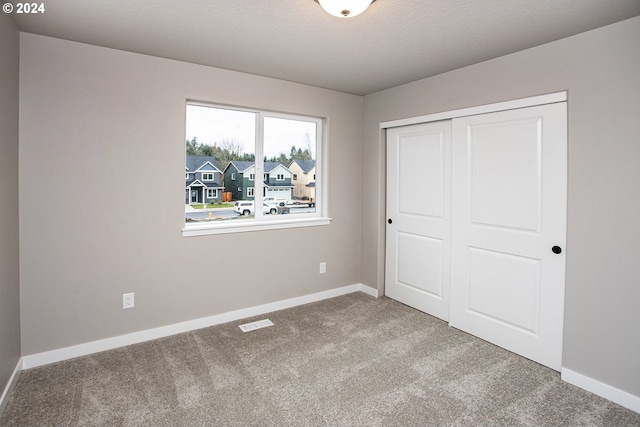 unfurnished bedroom with carpet, a textured ceiling, and a closet