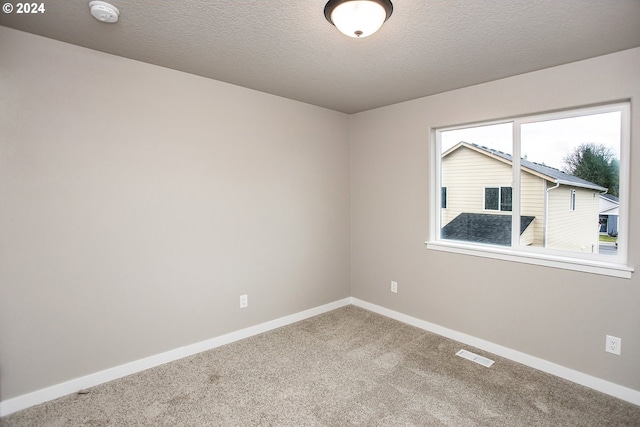 carpeted empty room featuring a textured ceiling