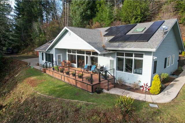 rear view of property with solar panels, a yard, and a deck