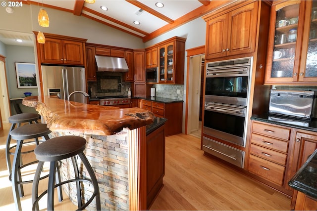 kitchen featuring hanging light fixtures, a breakfast bar, dark stone counters, and appliances with stainless steel finishes