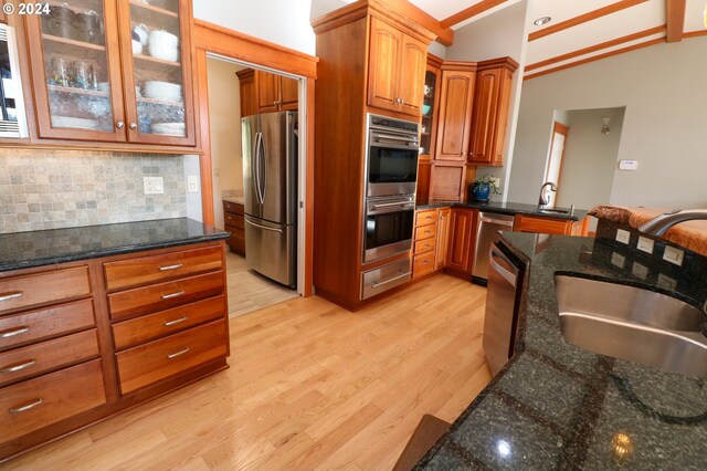 kitchen with lofted ceiling, sink, light hardwood / wood-style flooring, tasteful backsplash, and stainless steel appliances