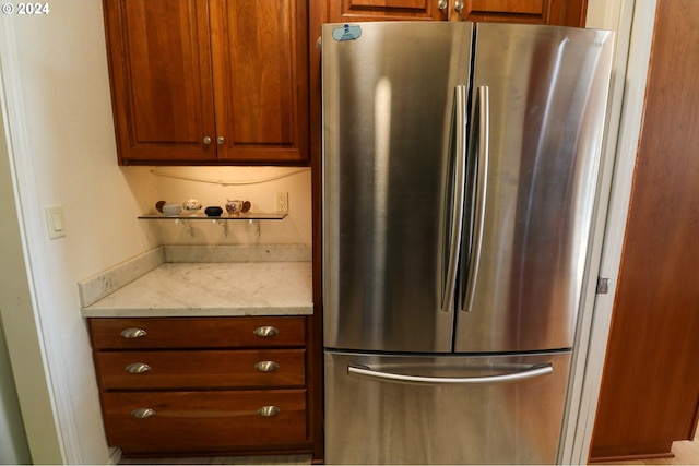 kitchen featuring light stone countertops and stainless steel refrigerator