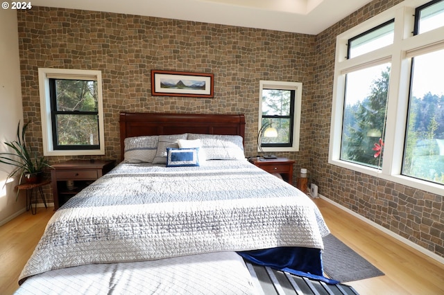 bedroom with hardwood / wood-style floors and brick wall