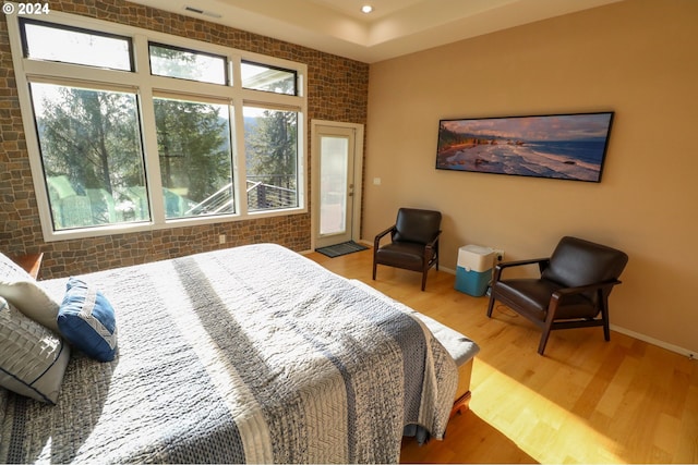 bedroom featuring wood-type flooring and brick wall