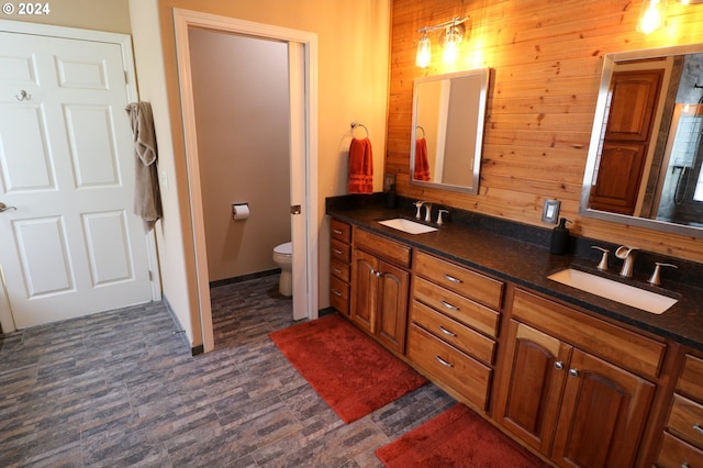 bathroom with vanity, toilet, and wood walls