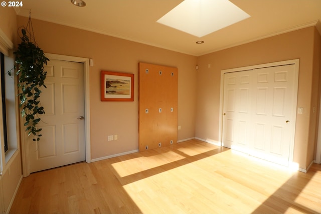 unfurnished bedroom featuring a skylight, light hardwood / wood-style flooring, and ornamental molding