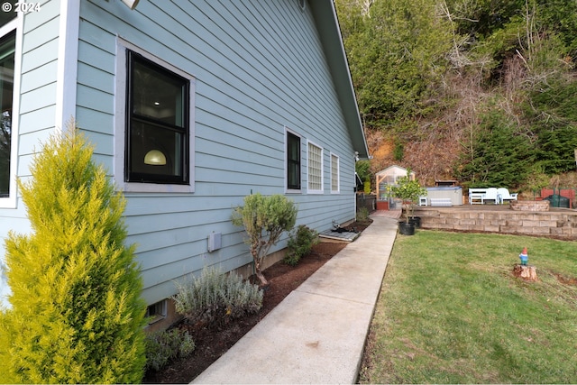 view of side of home featuring a patio area and a lawn