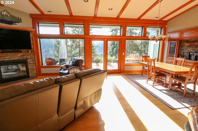 living room with a stone fireplace, high vaulted ceiling, a notable chandelier, and light wood-type flooring