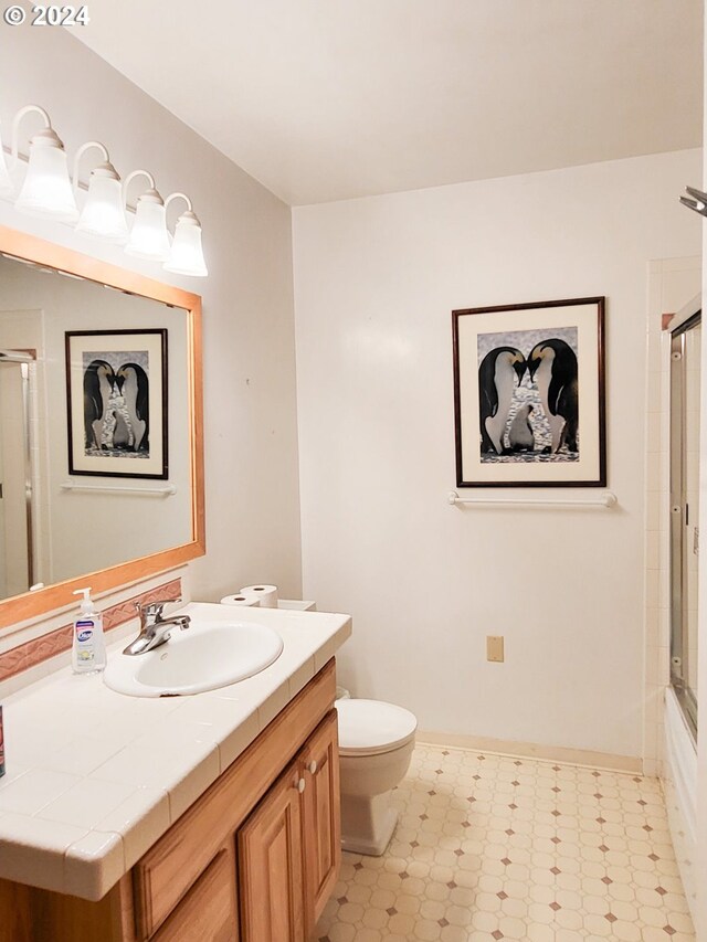 full bathroom with vanity, combined bath / shower with glass door, and toilet