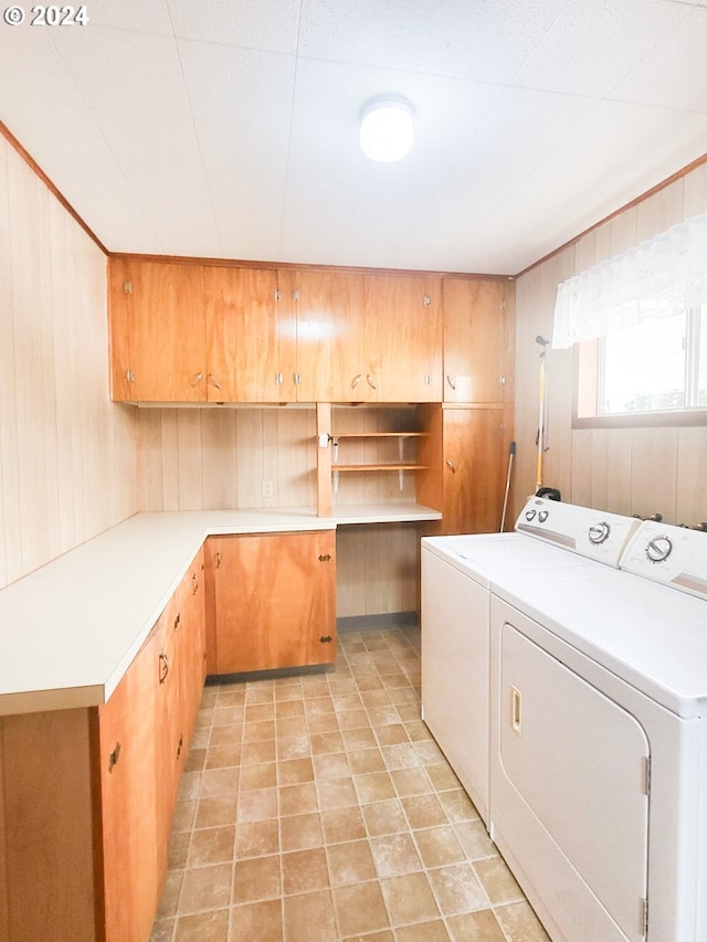 clothes washing area featuring cabinets, independent washer and dryer, and wood walls