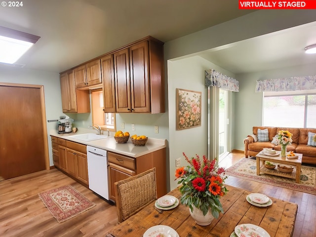 kitchen with light wood-type flooring, white dishwasher, and sink