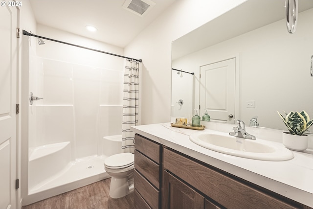 bathroom with curtained shower, toilet, wood finished floors, and visible vents