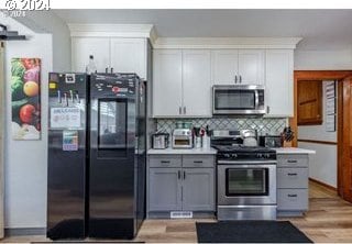 kitchen featuring appliances with stainless steel finishes, light wood-type flooring, gray cabinets, and tasteful backsplash