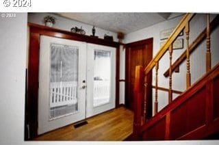 entrance foyer with french doors, a textured ceiling, and hardwood / wood-style floors