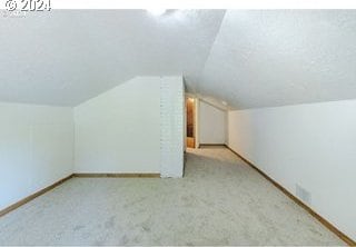 bonus room with light colored carpet and lofted ceiling