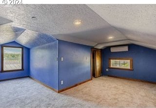 bonus room featuring carpet flooring, a wall mounted air conditioner, lofted ceiling, and a textured ceiling