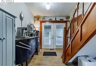 doorway featuring french doors, a textured ceiling, and light wood-type flooring