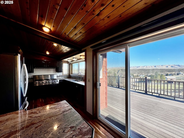 kitchen featuring backsplash, wooden ceiling, freestanding refrigerator, a mountain view, and a sink