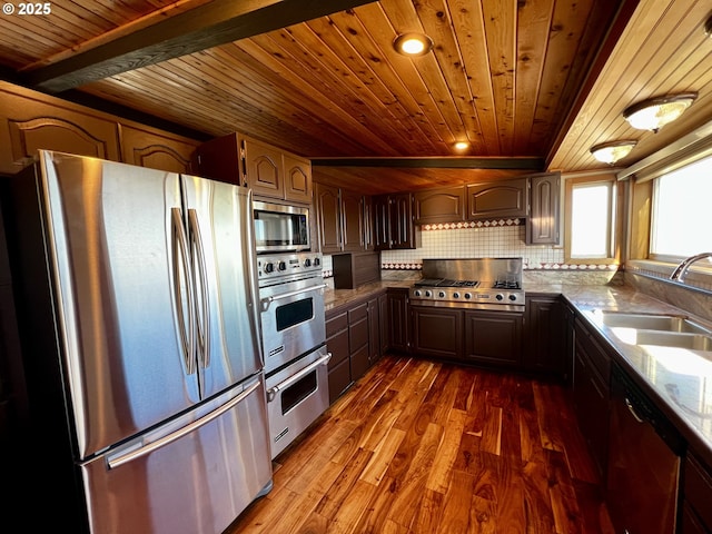 kitchen featuring decorative backsplash, sink, beamed ceiling, appliances with stainless steel finishes, and light stone counters