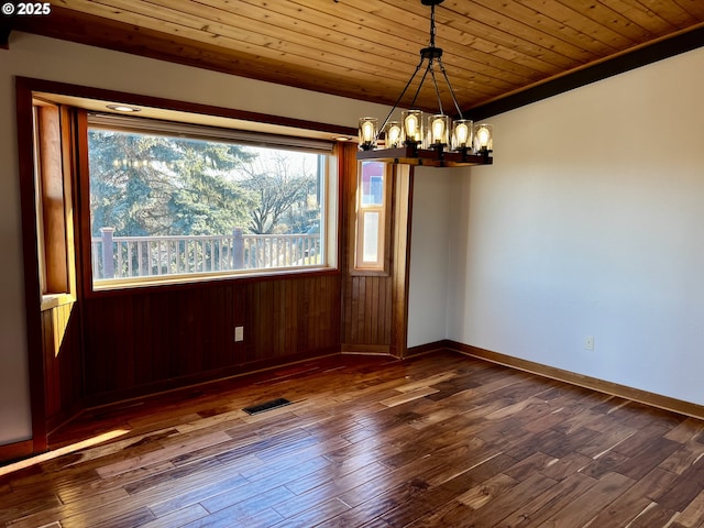 unfurnished dining area with dark wood-type flooring, wood ceiling, crown molding, and an inviting chandelier