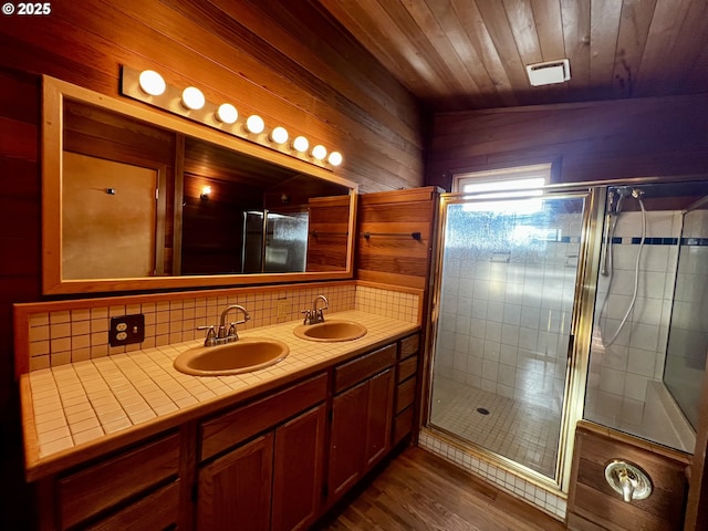 bathroom featuring a sink, visible vents, backsplash, and a stall shower