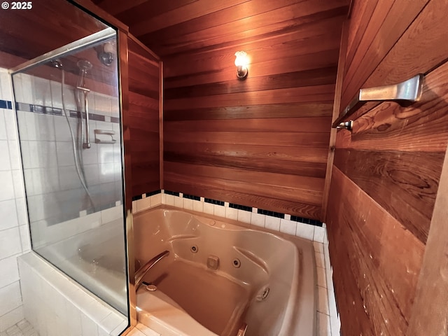 full bathroom with tiled shower, wood walls, and a whirlpool tub