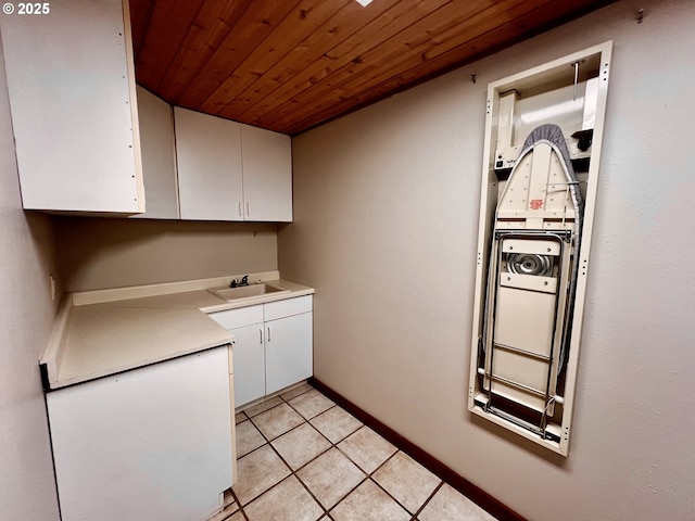 kitchen featuring light countertops, wooden ceiling, light tile patterned flooring, white cabinets, and a sink