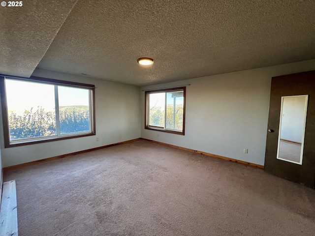 spare room featuring carpet, baseboards, and a textured ceiling