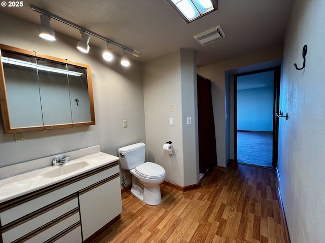 bathroom with visible vents, baseboards, toilet, wood finished floors, and vanity