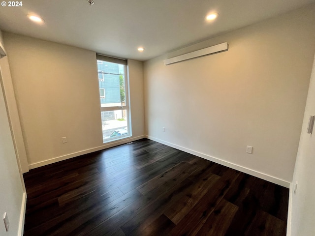 unfurnished room featuring a wall mounted AC and dark wood-type flooring