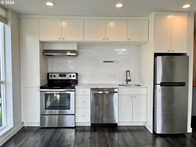 kitchen featuring wall chimney range hood, appliances with stainless steel finishes, sink, and dark hardwood / wood-style flooring