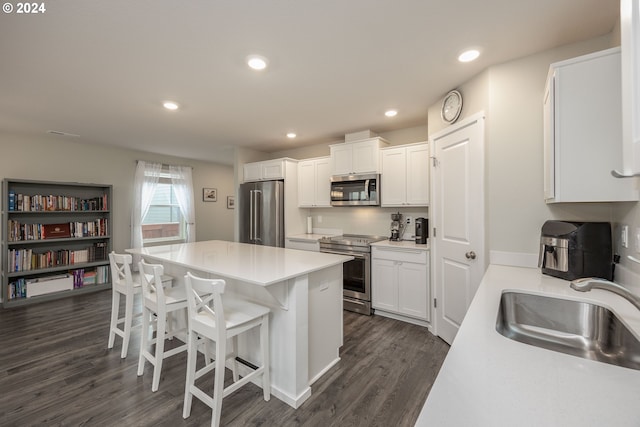 kitchen with sink, dark hardwood / wood-style floors, a breakfast bar area, white cabinets, and appliances with stainless steel finishes