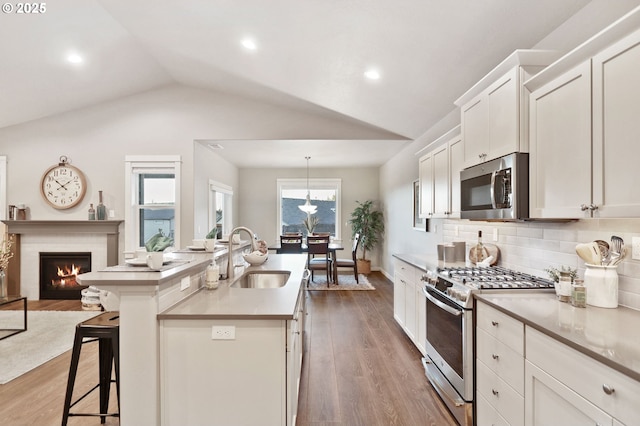 kitchen with a kitchen island with sink, sink, tasteful backsplash, a kitchen bar, and stainless steel appliances