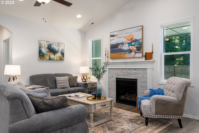 living room with vaulted ceiling, hardwood / wood-style flooring, a brick fireplace, and ceiling fan