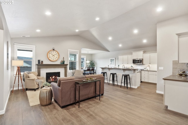 living room featuring light hardwood / wood-style floors, a wealth of natural light, and vaulted ceiling