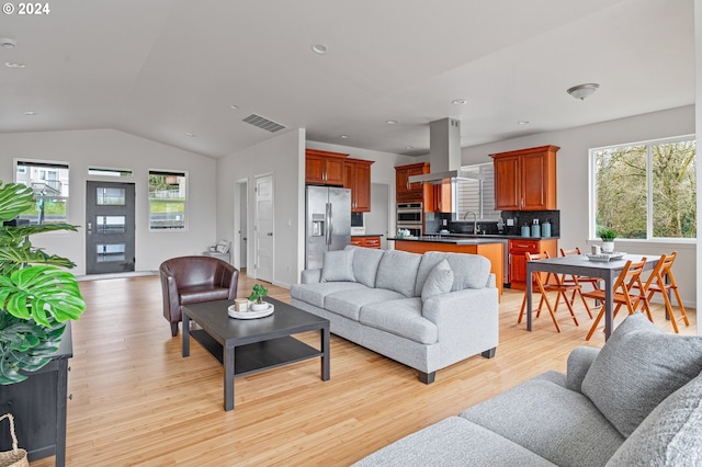 living room with light hardwood / wood-style flooring, lofted ceiling, and sink