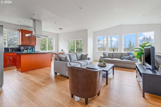 living room featuring light hardwood / wood-style flooring, vaulted ceiling, and sink