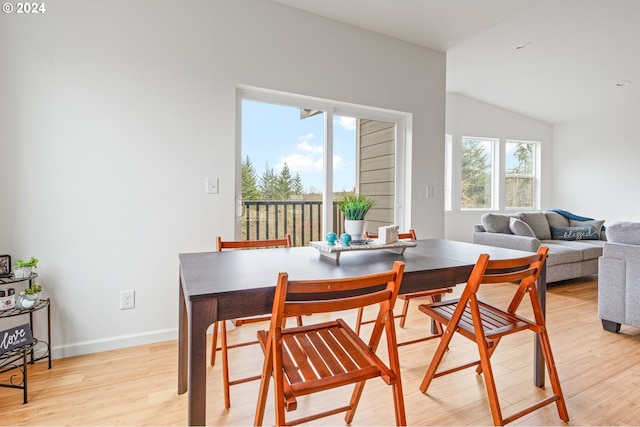 dining room featuring light hardwood / wood-style floors, vaulted ceiling, and a healthy amount of sunlight