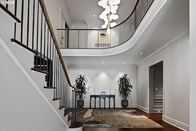 entrance foyer featuring crown molding, a towering ceiling, dark hardwood / wood-style floors, and an inviting chandelier