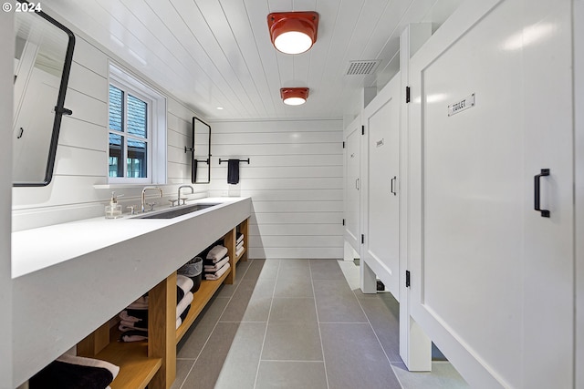 bathroom with tile patterned flooring, vanity, and wood walls