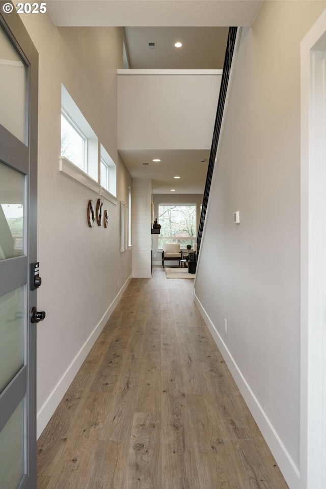 hallway featuring a towering ceiling and light hardwood / wood-style flooring