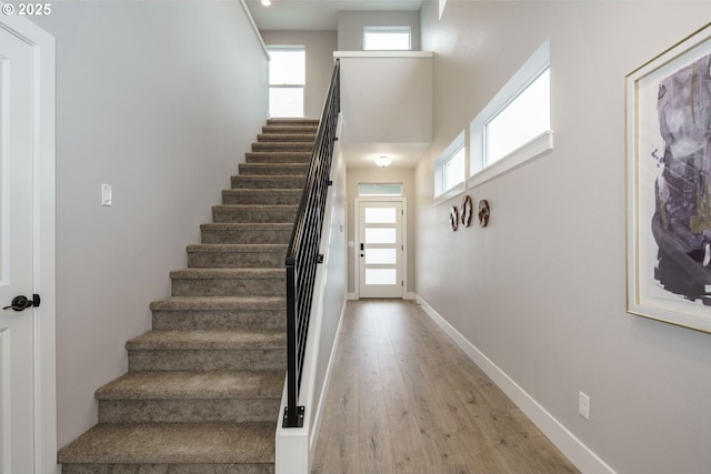 stairs with a healthy amount of sunlight, a towering ceiling, and hardwood / wood-style flooring