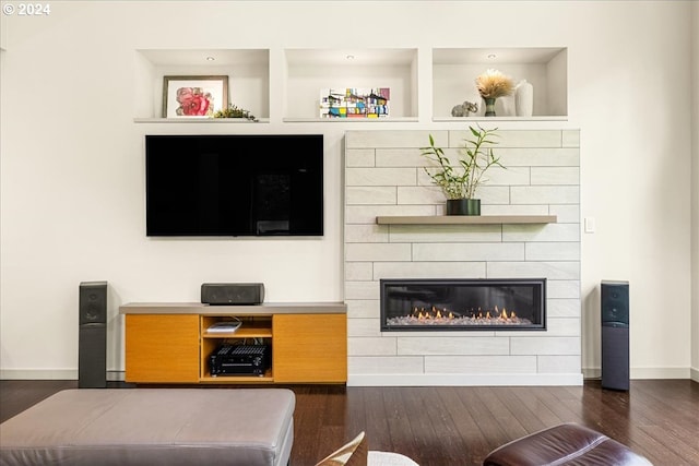 living room with built in features, dark wood-type flooring, and a fireplace