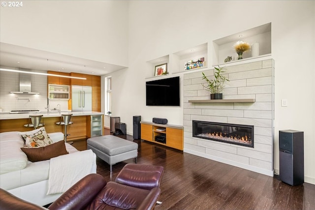 living room featuring a fireplace, dark wood-type flooring, a high ceiling, and sink