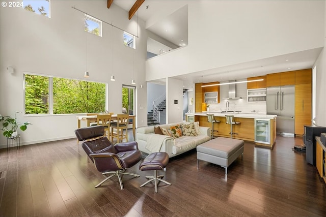 living room with a wealth of natural light, sink, a towering ceiling, and wood-type flooring